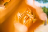 A close-up view of a hand performing a symbolic gesture surrounded by a warm golden-orange glow. The focus is on the hand, with the background softly blurred, creating an ethereal and serene atmosphere.