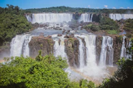 The thundering Victoria Falls cascading into mist, framed by lush green foliage.