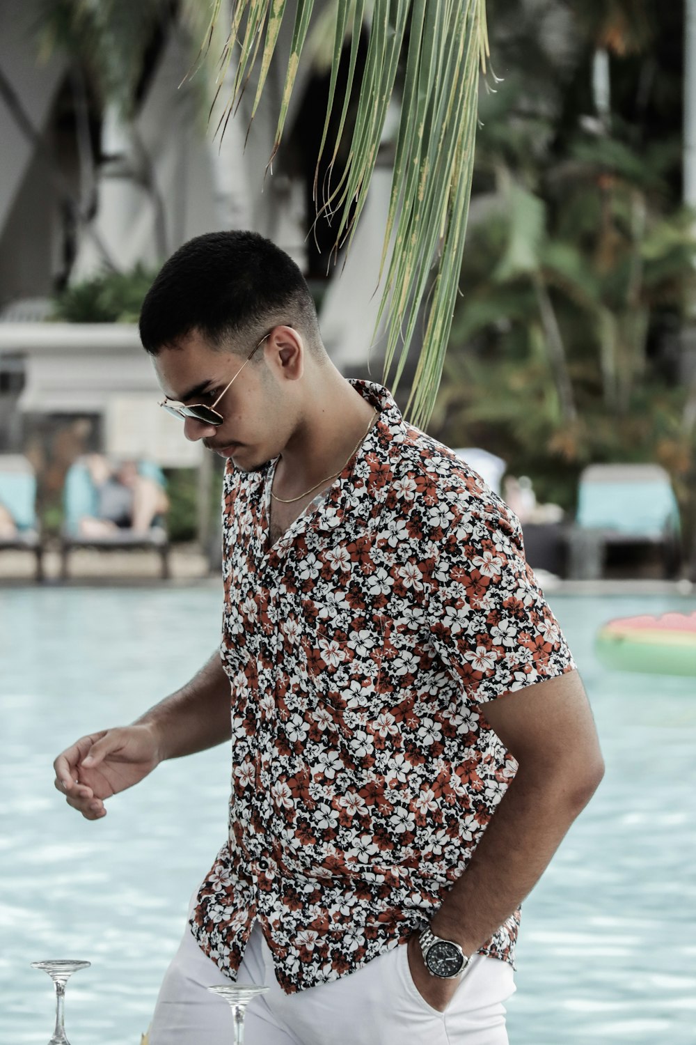 Un uomo in piedi vicino a una piscina che indossa occhiali da sole