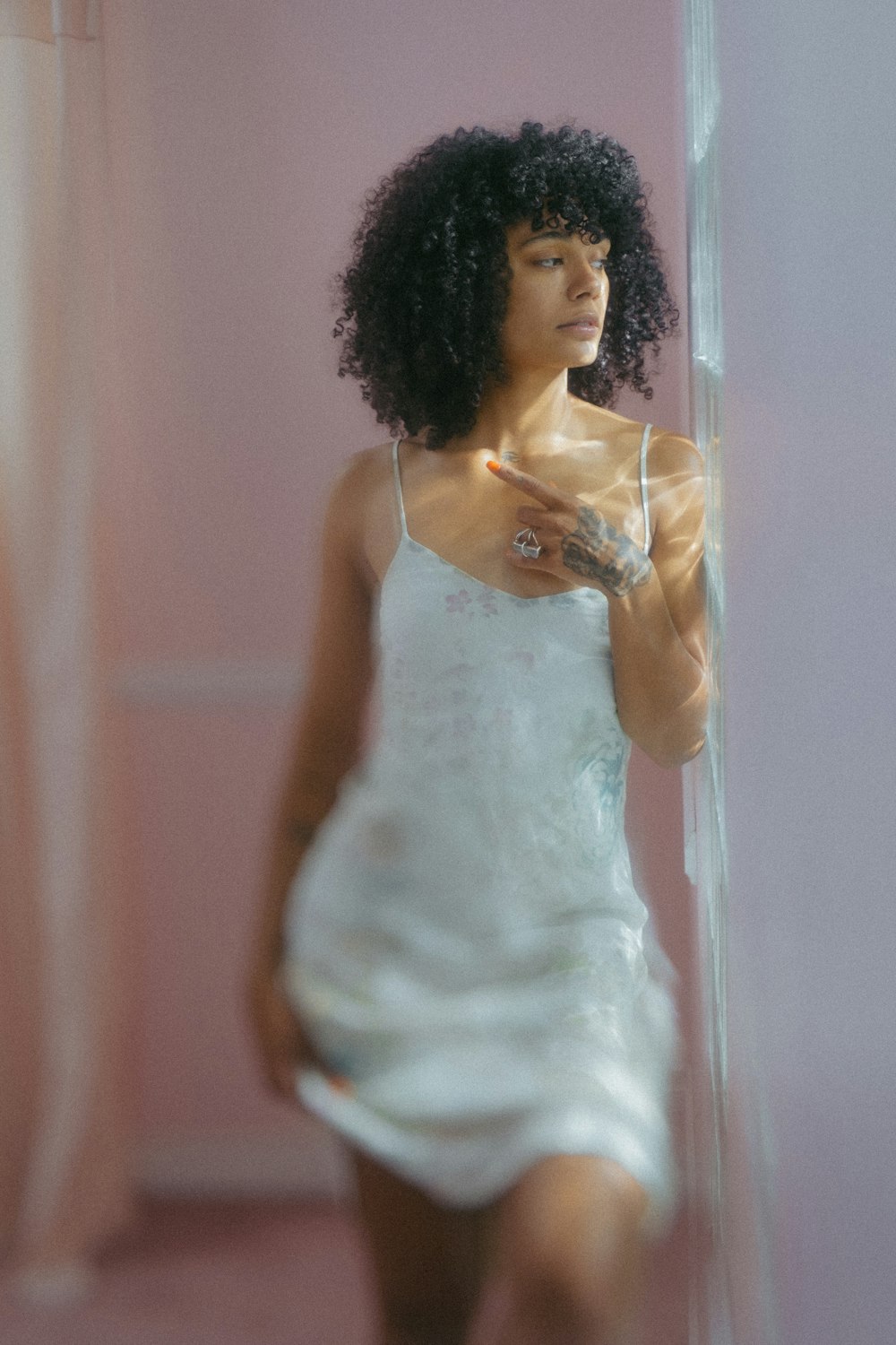 a woman in a white dress standing in front of a mirror