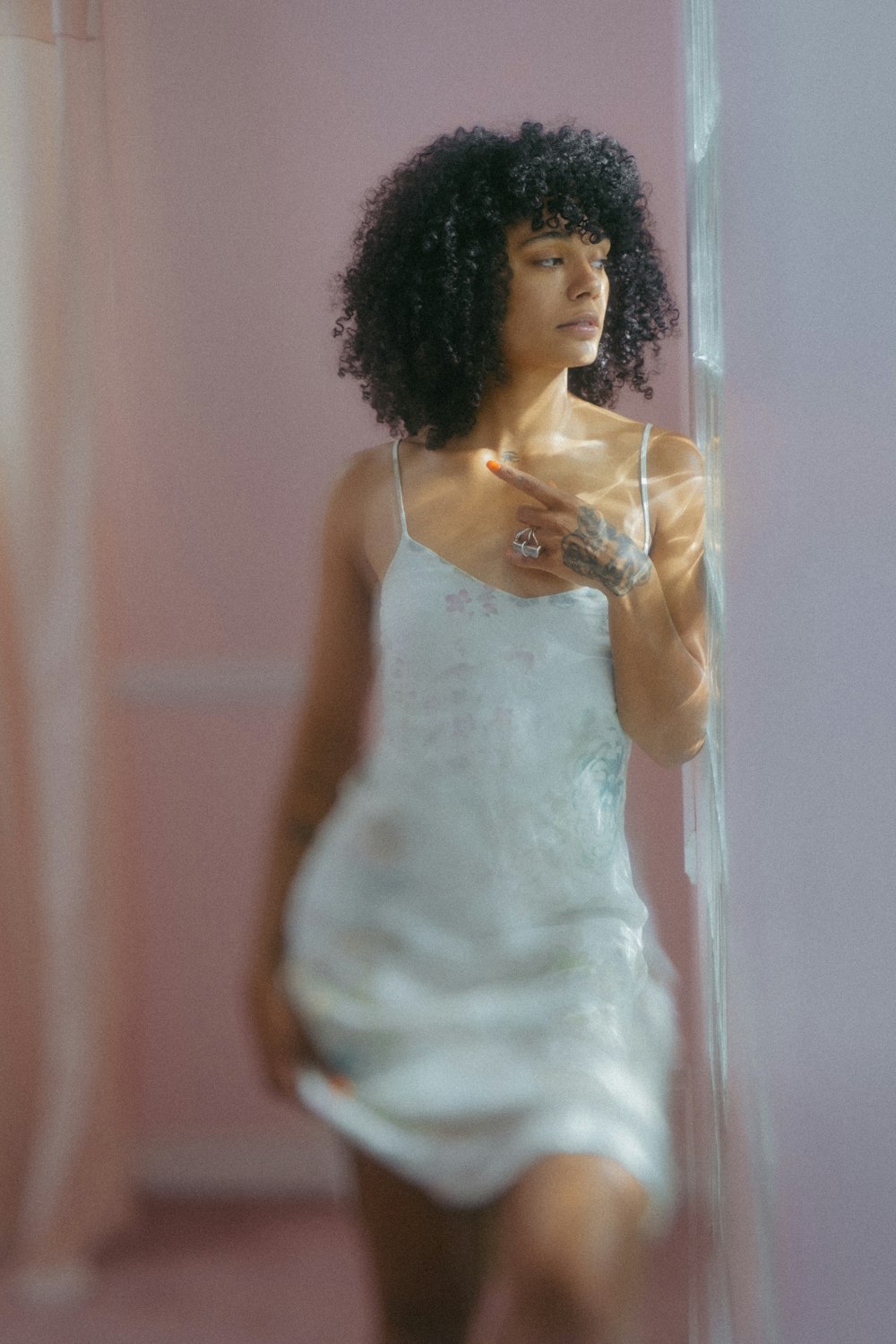 uma mulher em um vestido branco em pé na frente de um espelho