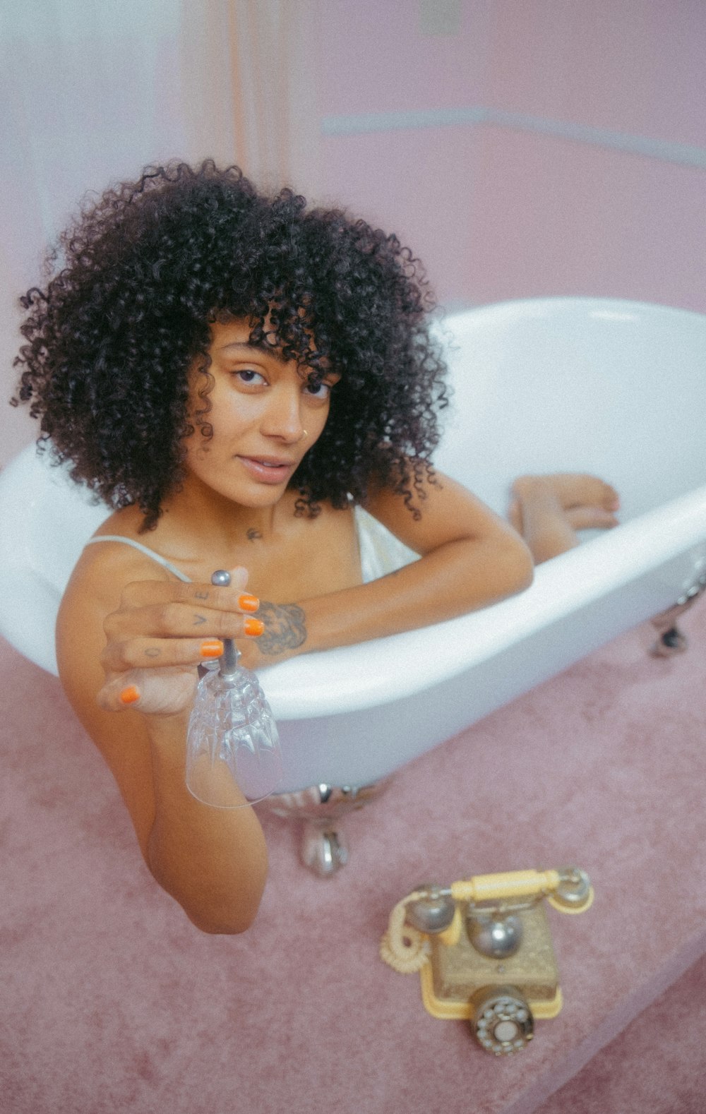 uma mulher sentada em uma banheira com um telefone ao lado dela