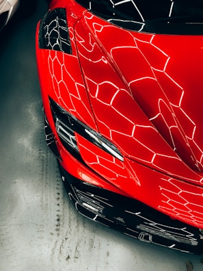 A vibrant red sports car wrapped with a sleek, modern geometric design.