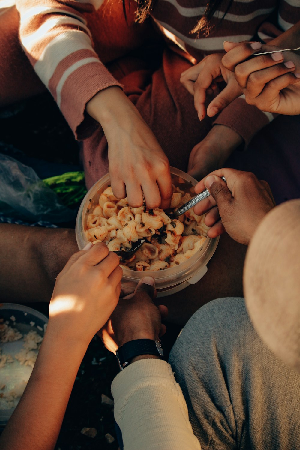 a group of people sitting around a bowl of food