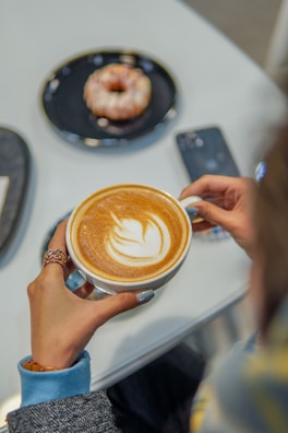 A customer using the Gojek app on their phone with a cup of coffee nearby.
