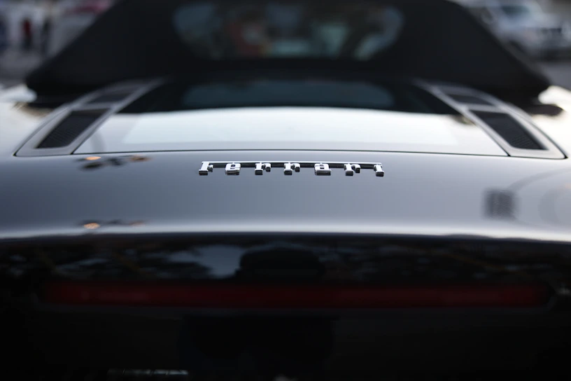 Close-up of a sleek black Ferrari with glistening reflective paint under soft cinematic lighting.