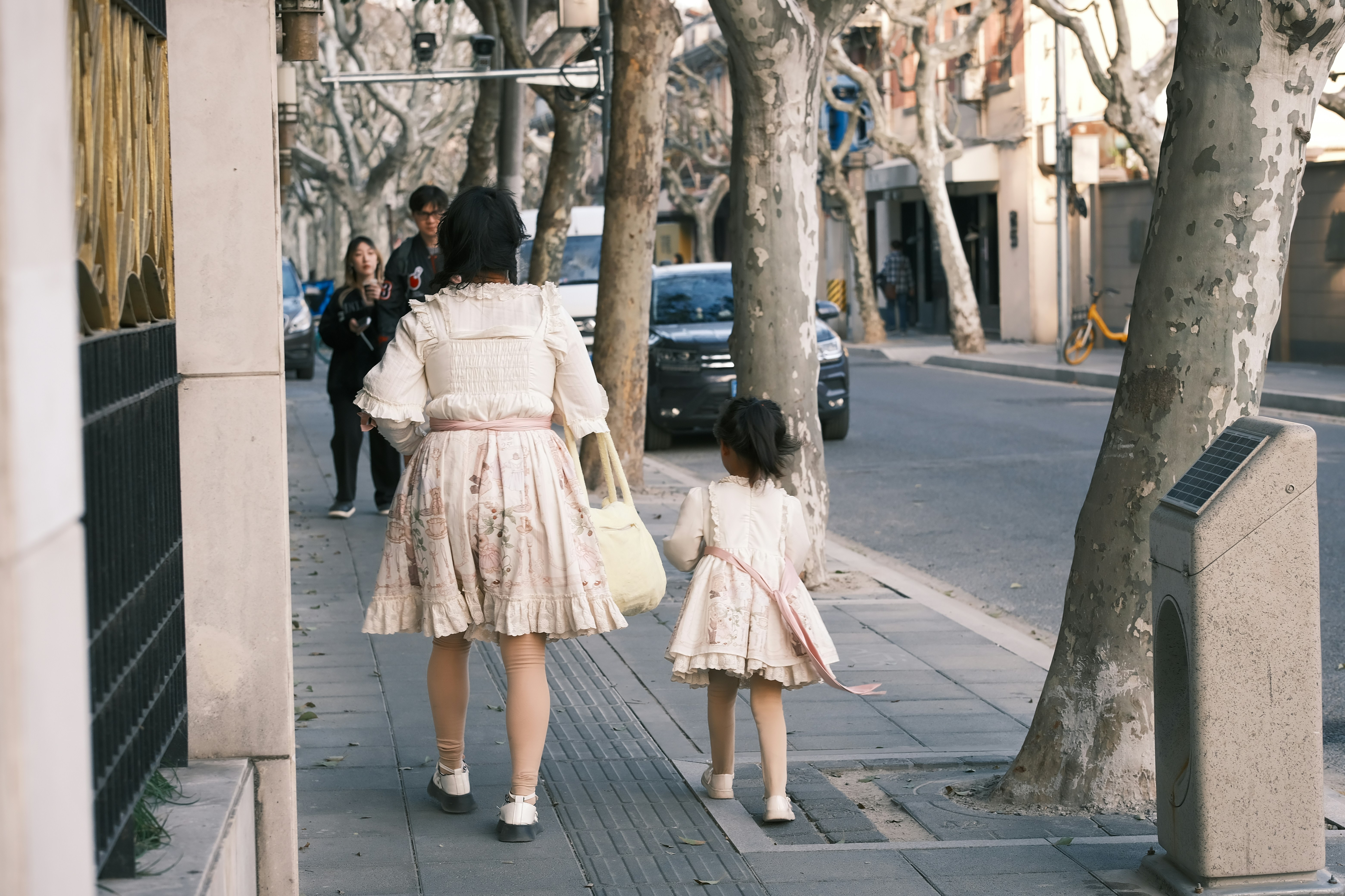 a woman and a little girl walking down a sidewalk
