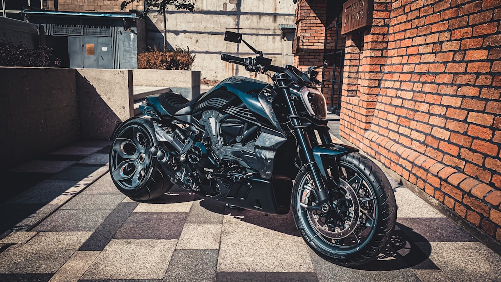 a black motorcycle parked next to a brick wall
