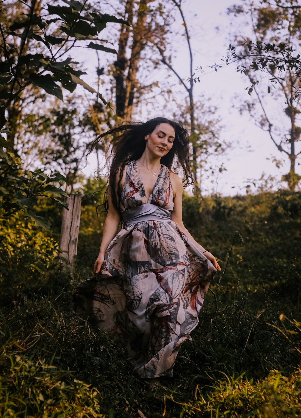 a woman in a dress walking through a forest