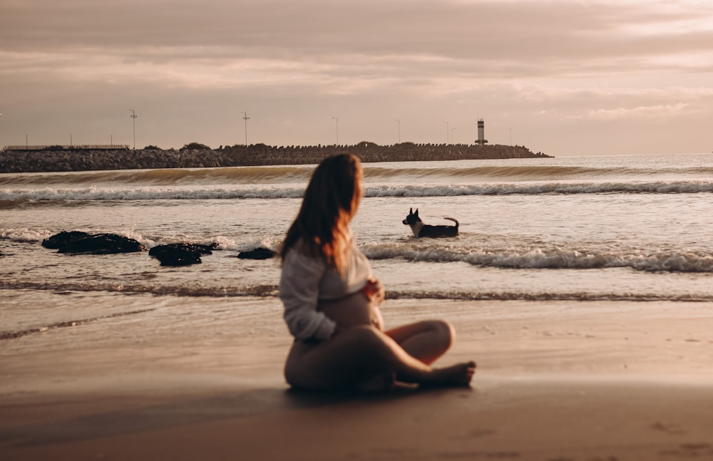 a woman sitting on the beach watching the waves