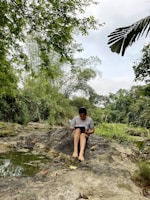 A person writing in a journal surrounded by nature.