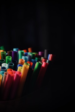 A collection of colorful markers arranged upright in a dark setting, showcasing a variety of vibrant hues such as orange, blue, yellow, green, and red.