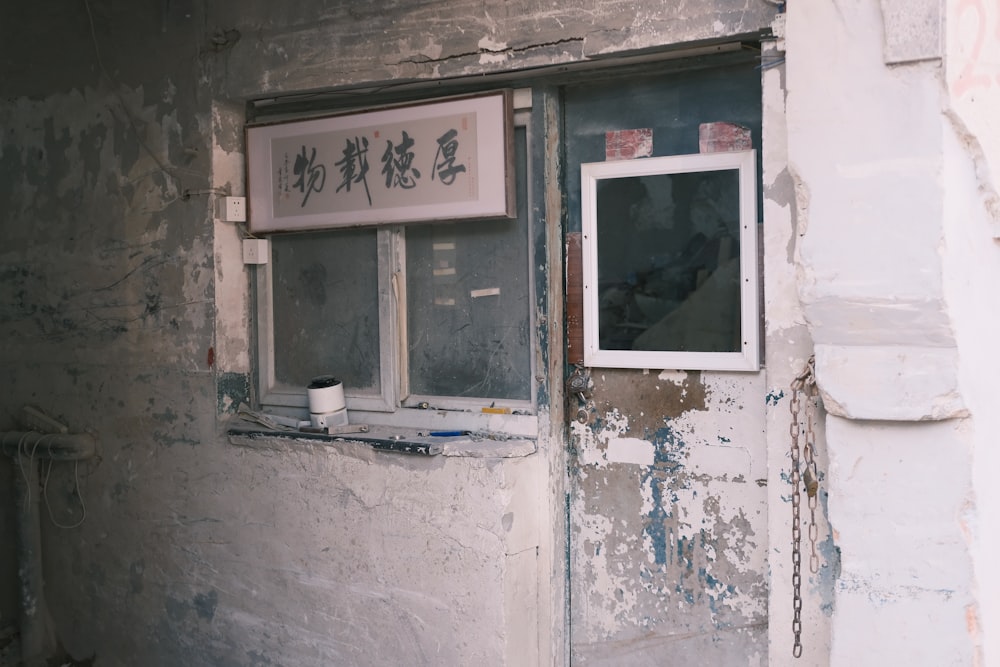 a dirty building with a window and a sign on it