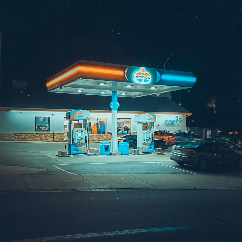 a gas station at night with cars parked in front of it