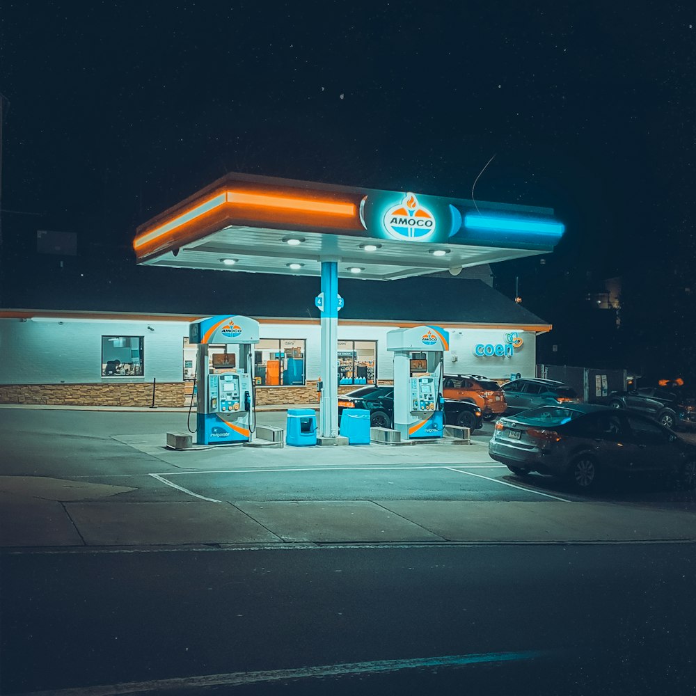 um posto de gasolina à noite com carros estacionados em frente a ele