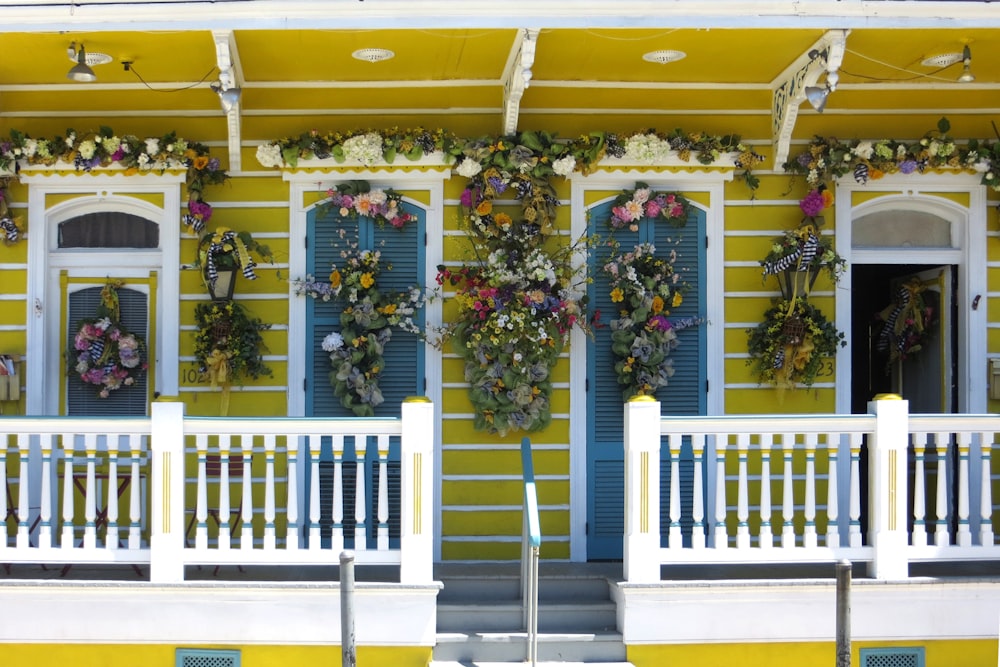 a yellow building with blue shutters and flowers on it