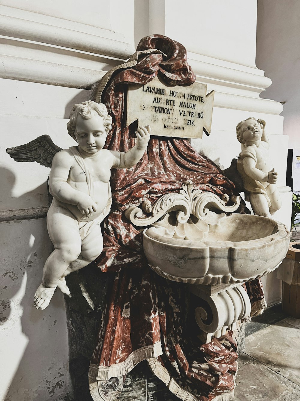 a statue of a cherub sitting next to a fountain