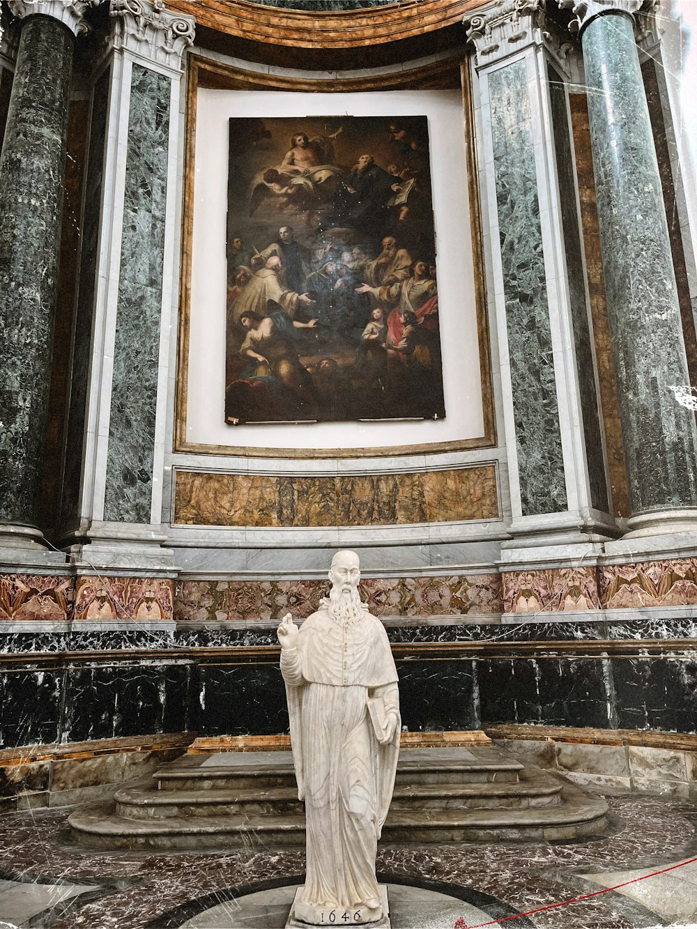 a statue of a man standing in front of a painting