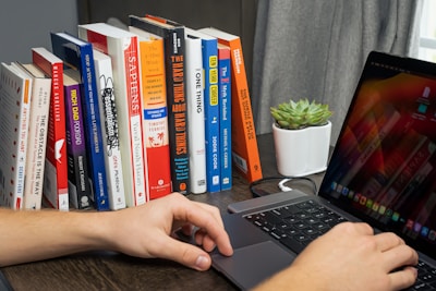 A person working on a laptop in a cozy workspace filled with plants and books.