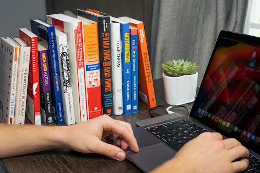 A person working on a laptop with AI-related graphics on the screen, surrounded by books and notes.