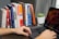 A happy student working on a laptop with books around.
