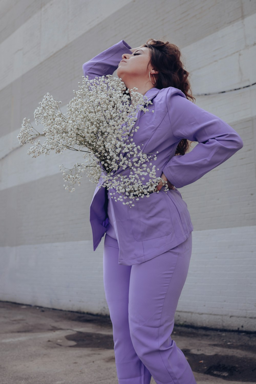 Une femme en costume violet tenant un bouquet de fleurs