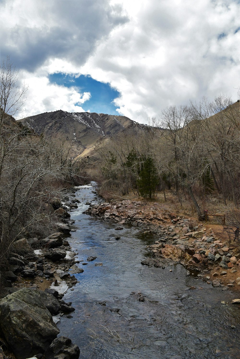 a stream running through a dry grass covered hillside