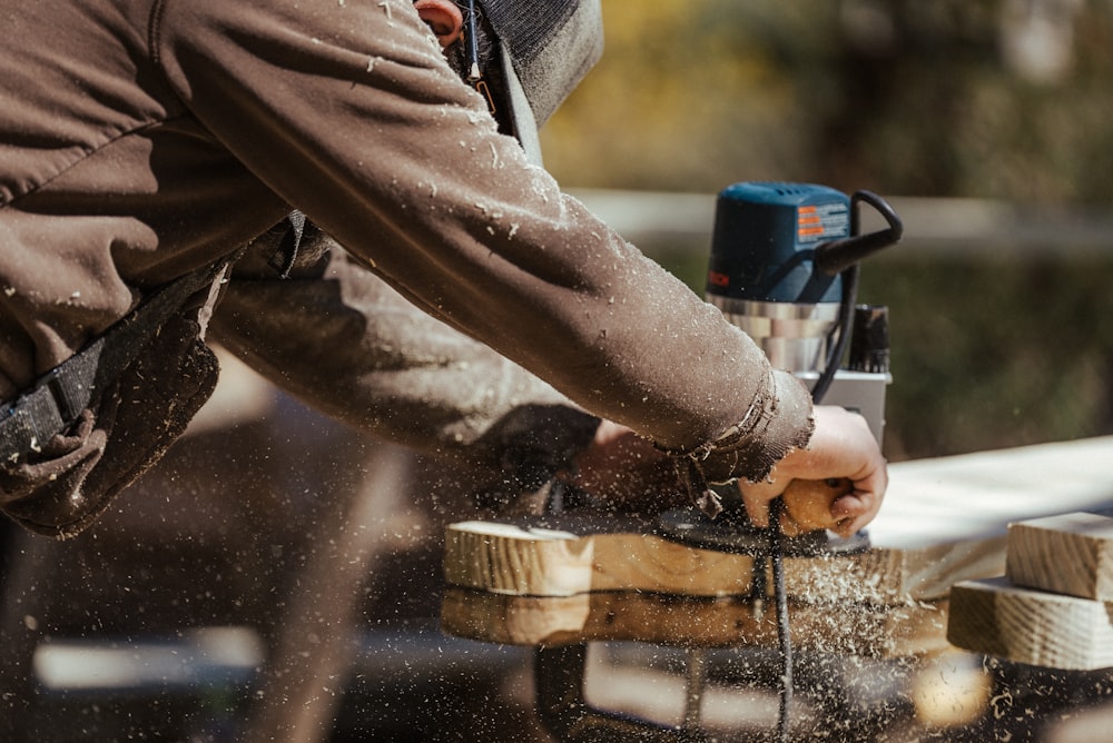 Un uomo che leviga un pezzo di legno con una levigatrice