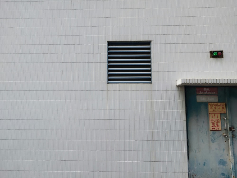 a white building with a blue door and a green light