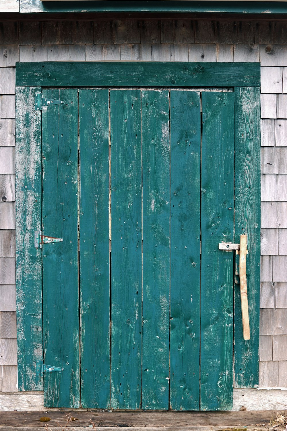a green door with a wooden handle on a house
