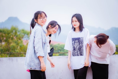 A group of women laughing together on a mountain trail with panoramic views.