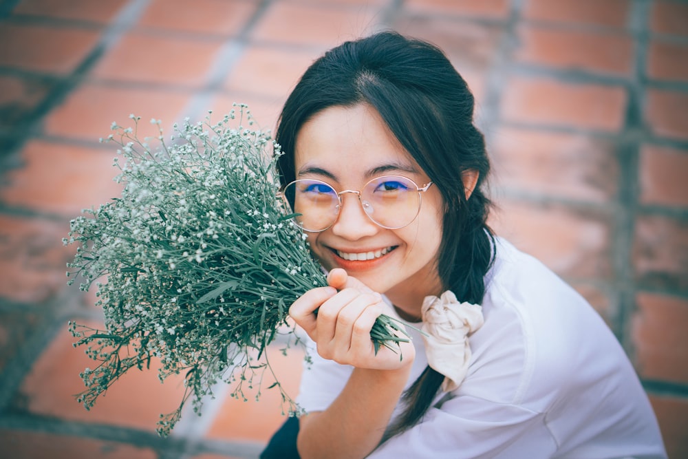 a woman wearing glasses holding a bunch of flowers