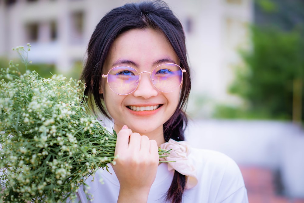 a woman wearing glasses holding a bunch of flowers