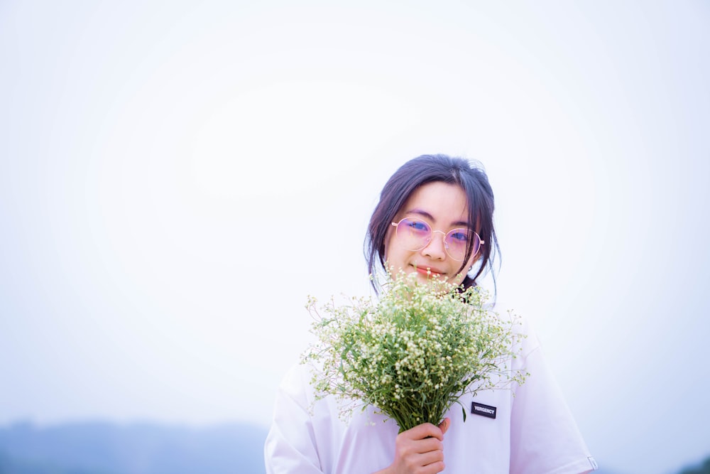 a woman holding a bunch of flowers in front of her face