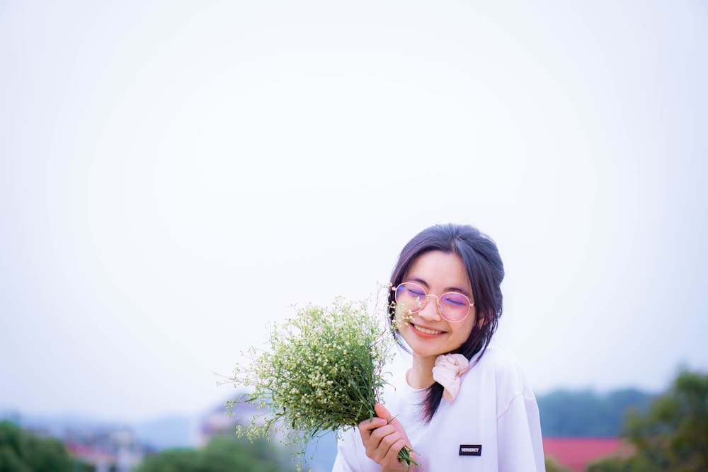 a woman wearing glasses holding a bunch of flowers