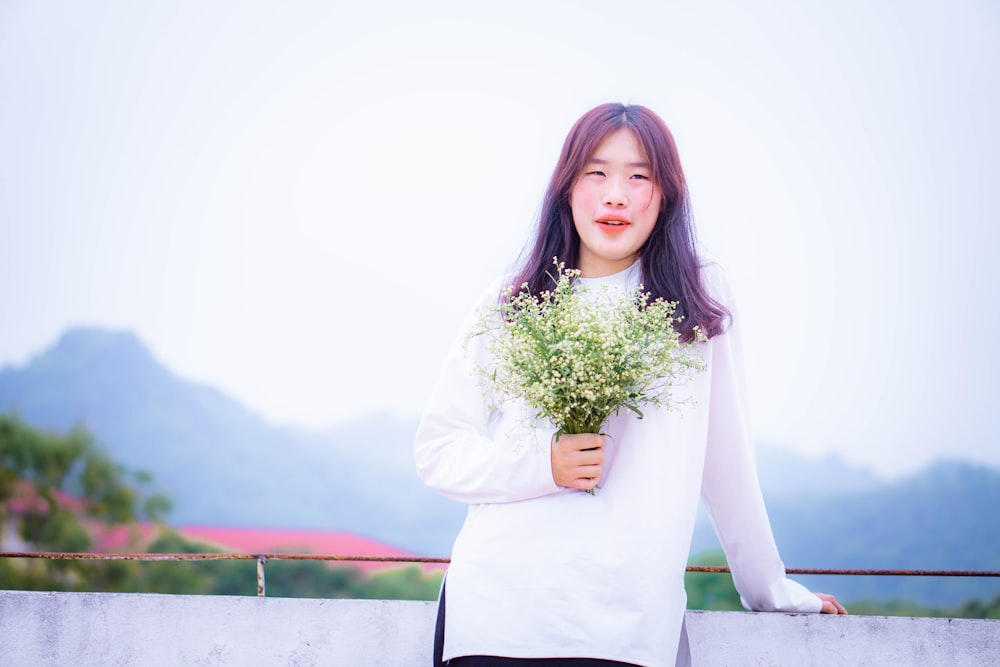 a woman holding a bunch of flowers in her hands