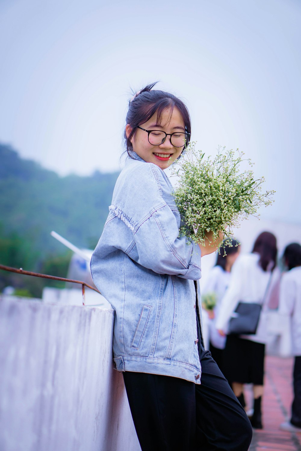 a woman leaning against a wall holding a plant