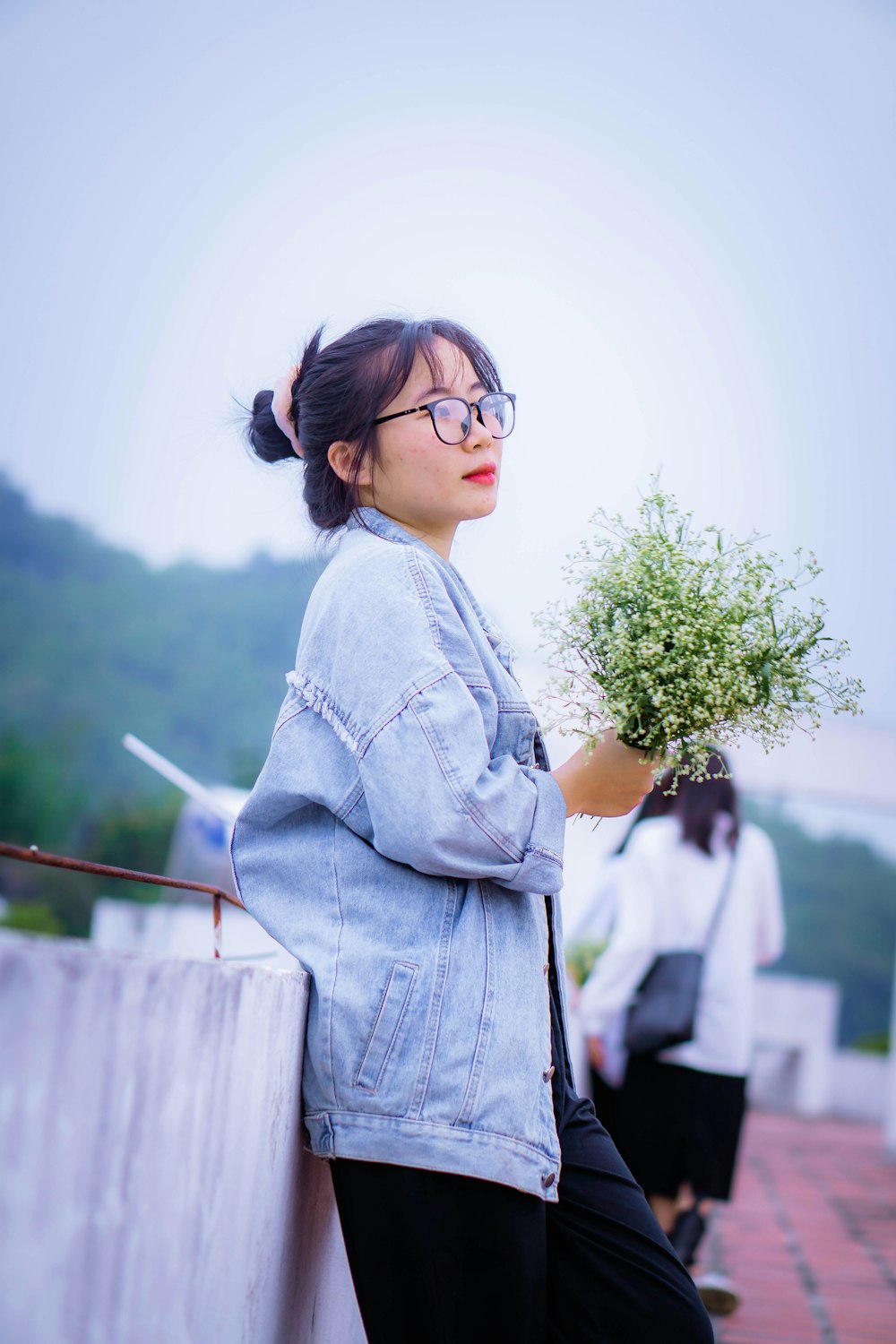 a woman wearing glasses holding a plant in her hand