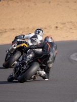 Riders in full safety gear enjoying a high-speed turn on the track.