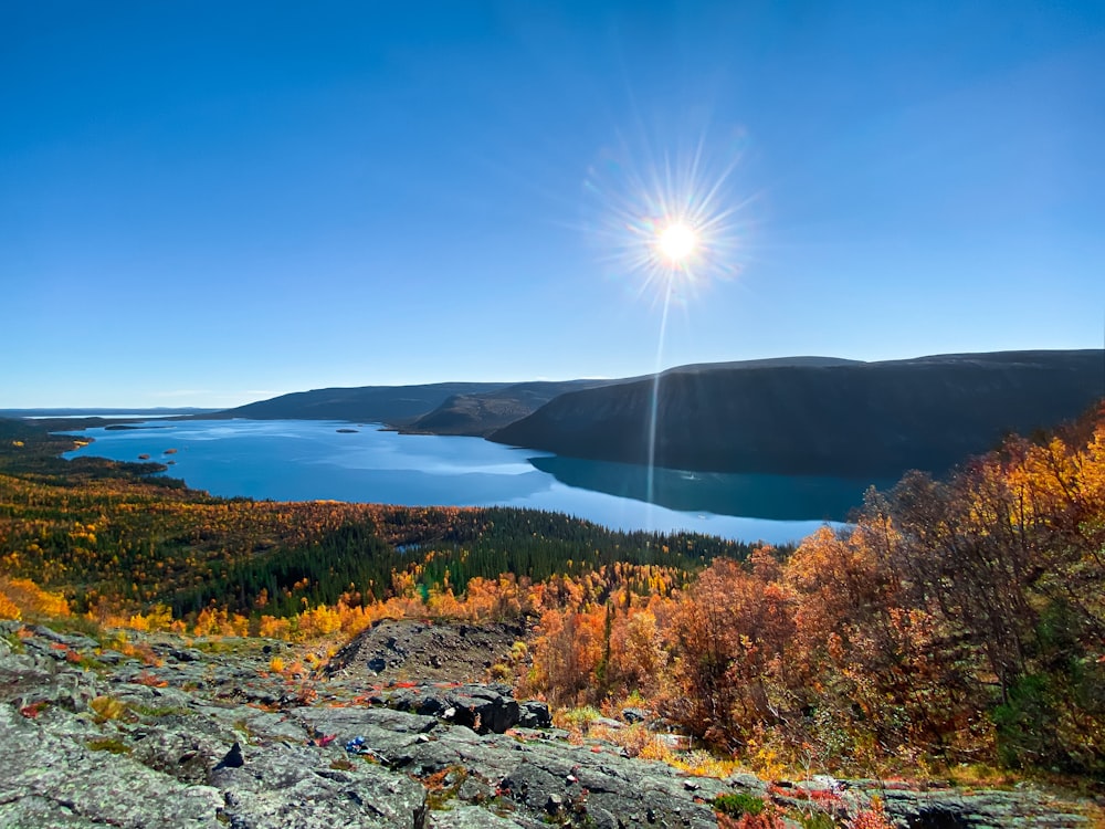 the sun is shining over a lake surrounded by trees