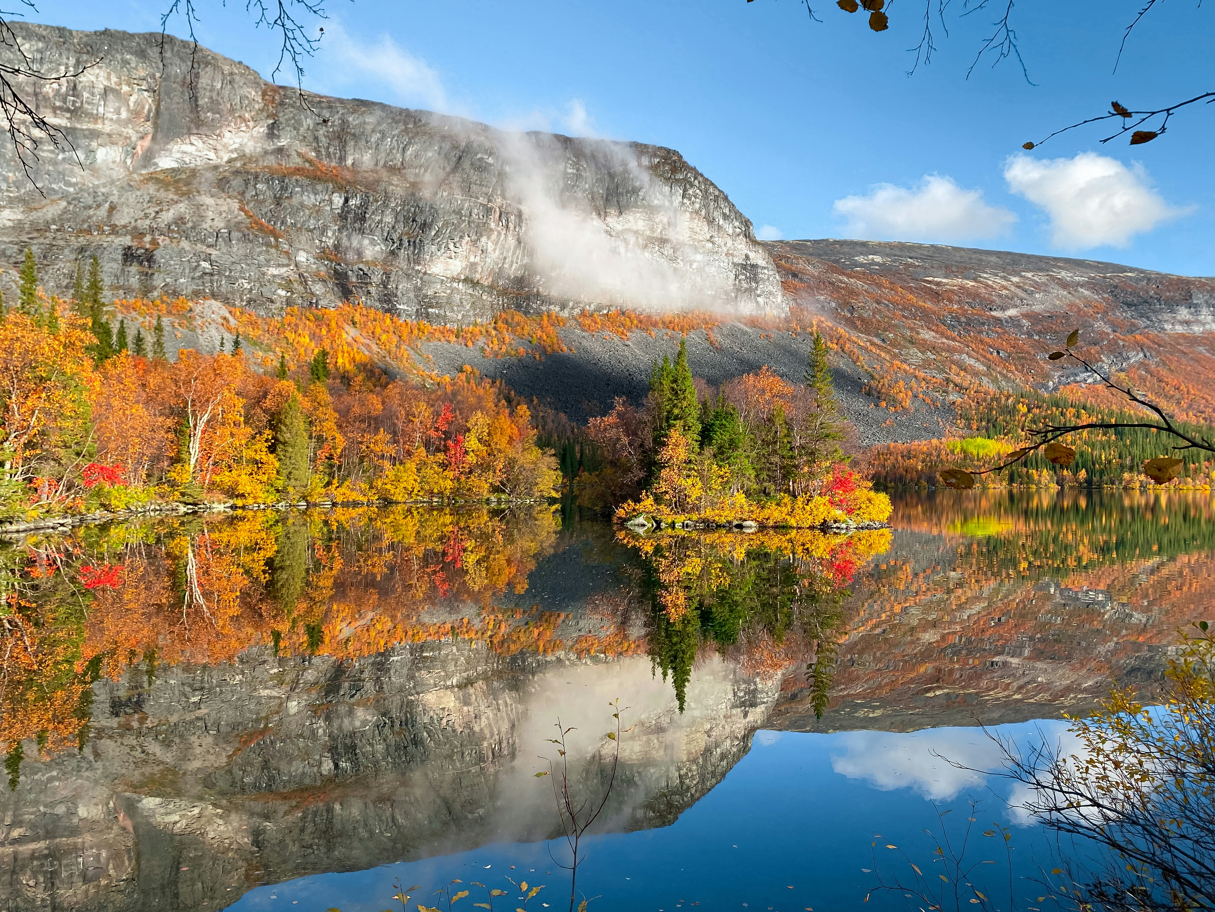 a lake surrounded by a mountain covered in fall foliage