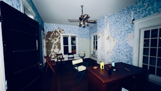 a room with a table, chairs and a ceiling fan
