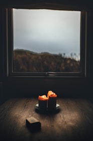 a candle sitting on top of a wooden table next to a window