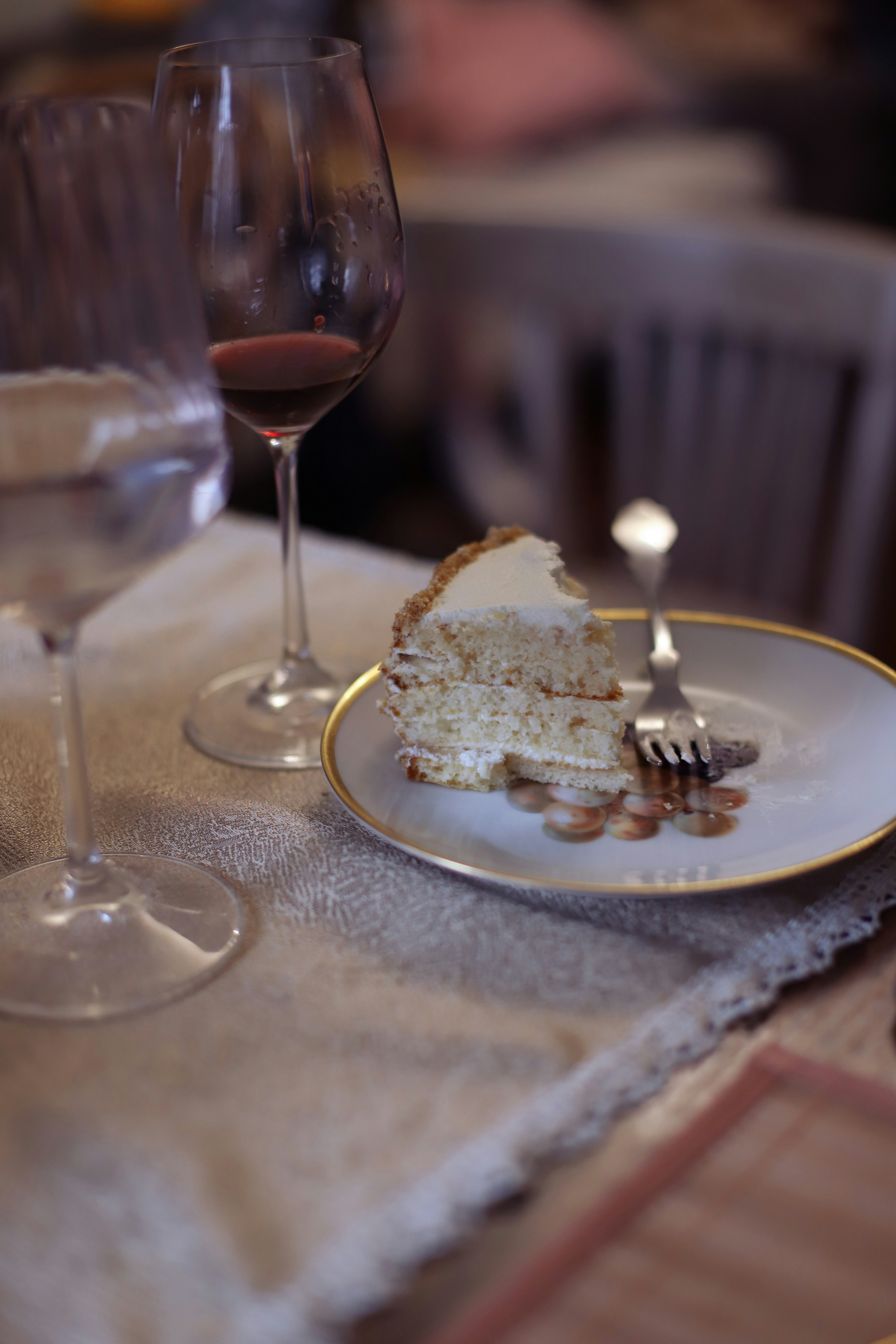 a slice of cake on a plate next to a glass of wine