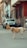 Two dogs are standing on a narrow street lined with parked cars and older buildings. The scene has an urban feel, with concrete surfaces and muted colors.