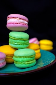 A stack of colorful macarons in dark pink and burgundy hues on a rustic wooden board.