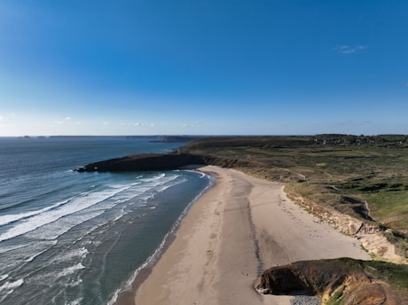 A scenic view of the beach at Costa Azul, with golden sand and gentle waves under a clear blue sky.