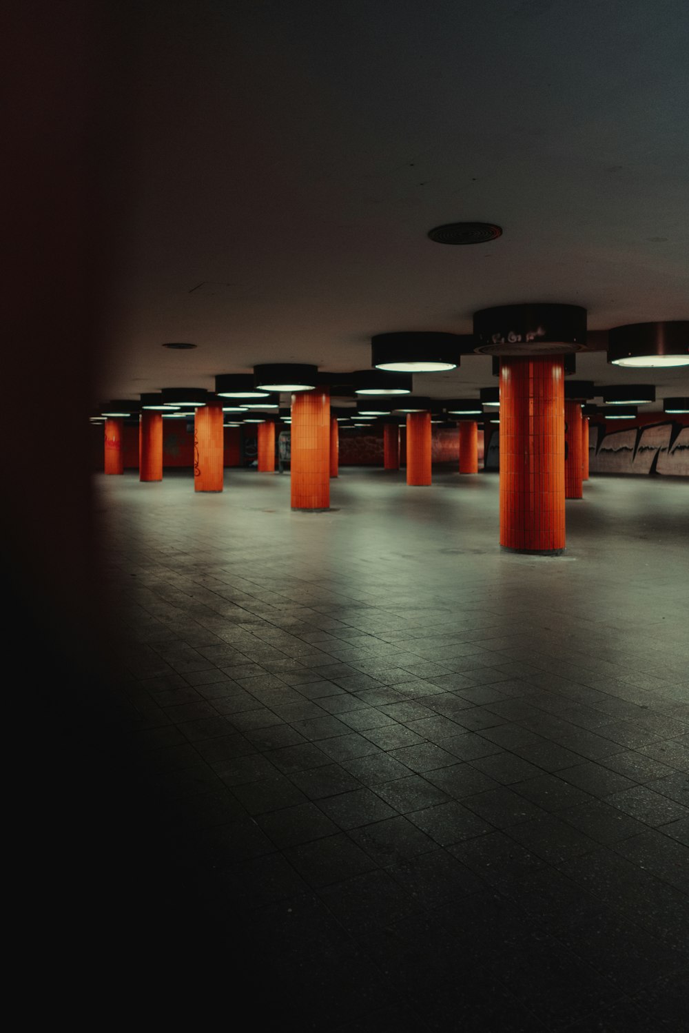 an empty room with orange columns and a black floor