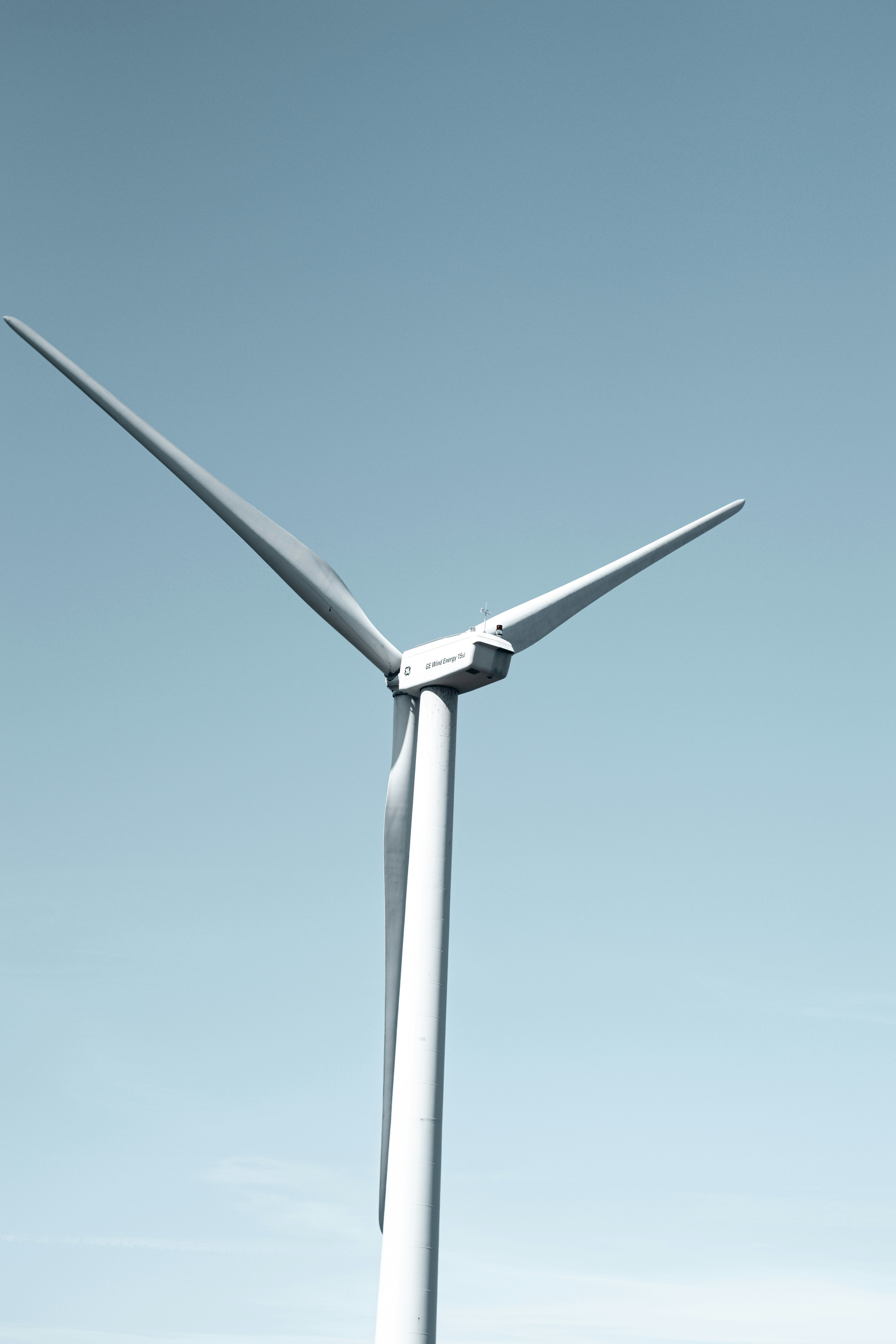 A large white wind turbine stands against a clear sky.