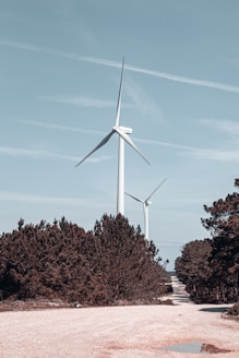a wind turbine on a dirt road surrounded by trees